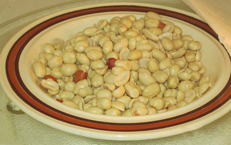 Lấy đĩa lạc ra khỏi lò vi sóng sau khi thực hiện cách rang đậu phộng bằng lò vi sóng